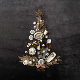 verschiedenes Porzellan von Gloria formt Christbaum: Tassen, Christbaumkugeln, Engel und Teller, dazwischen goldene Deko