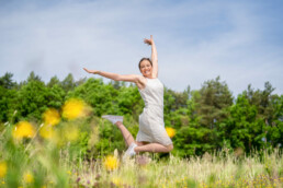 Spring Medical Fotografie Referenz, eine junge Frau springt lächelnd auf einer Blumenwiese und trägt Spring Medical Strümpfe