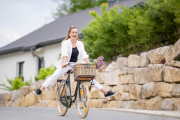 Spring Medical Fotografie Referenz, eine junge Frau fährt mit einem Fahrrad in dessen Korb frisch gepflückte Blumen sind, bergab, sie trägt Spring Medical Strümpfe