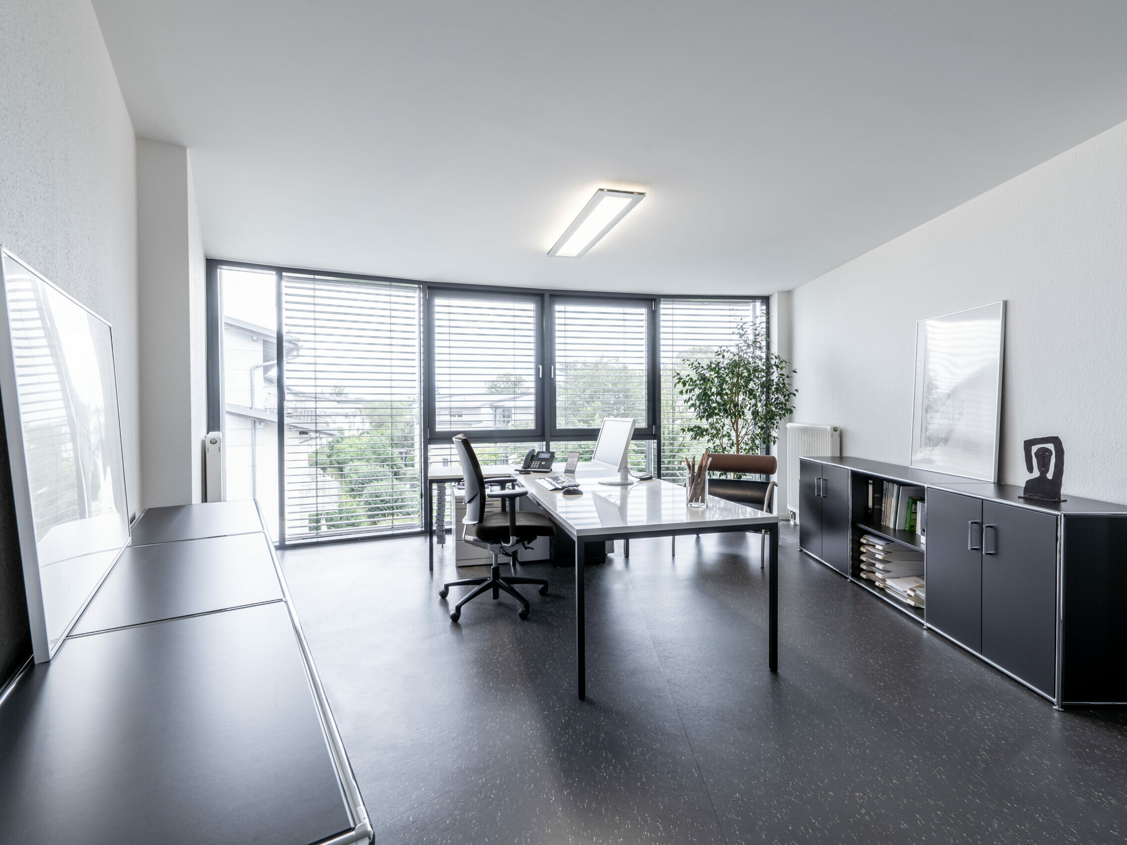 Büro der RSP Architekten, links und rechts stehen graue Regale, in der Mitte des Raumes steht vor einer Glasfront ein Schreibtisch mit PC