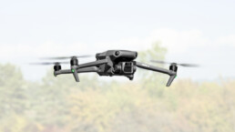 DJI Drohne Mavic 3 schwebt vor Büschen in der Luft