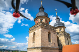 Die Stadtkirche Bayreuth aus der Luft fotografiert, man sieht zwei Propeller der Drohne am oberen Bildrand