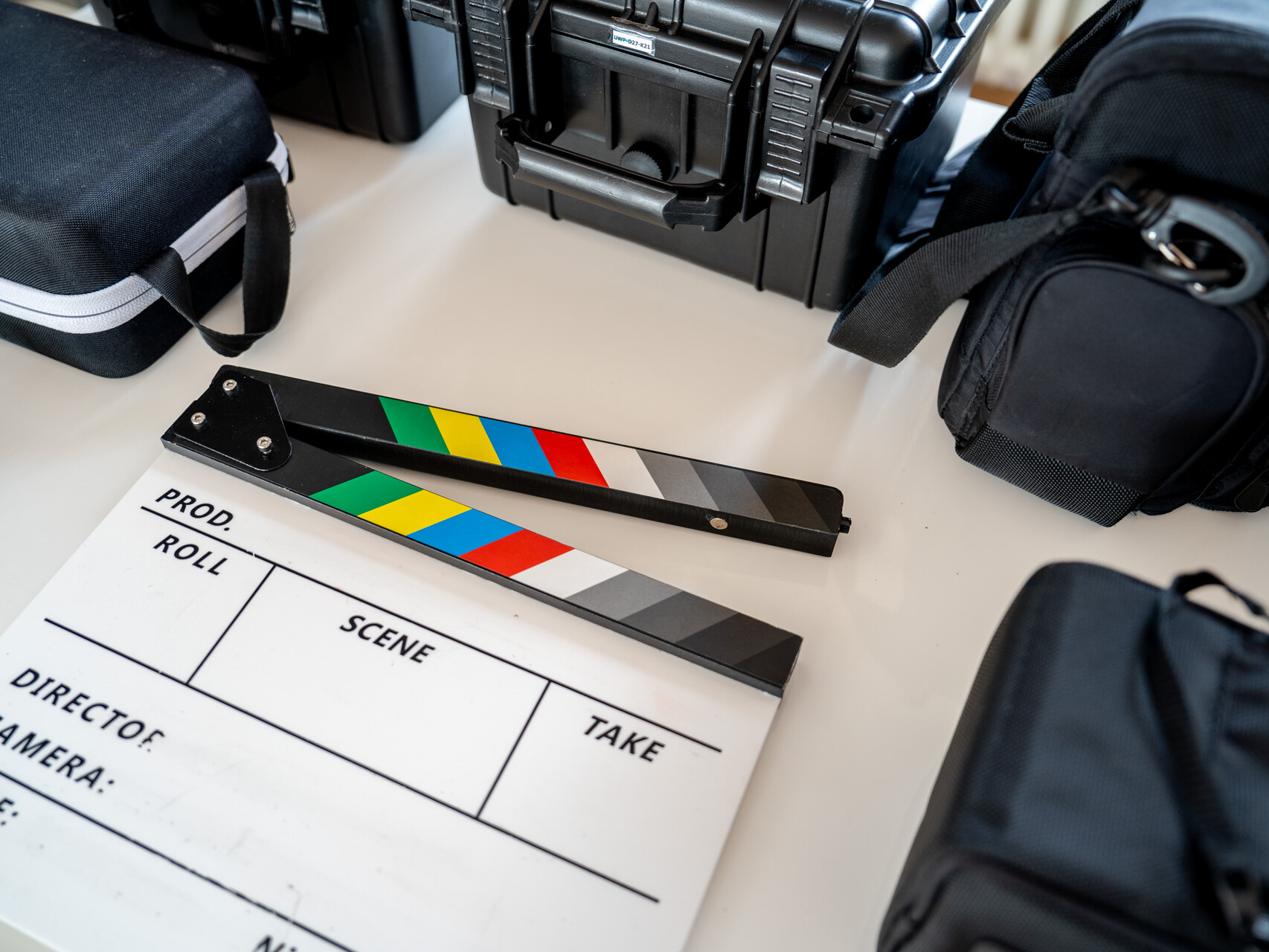 Filmklappe inmitten von Koffern und Taschen mit Equipment