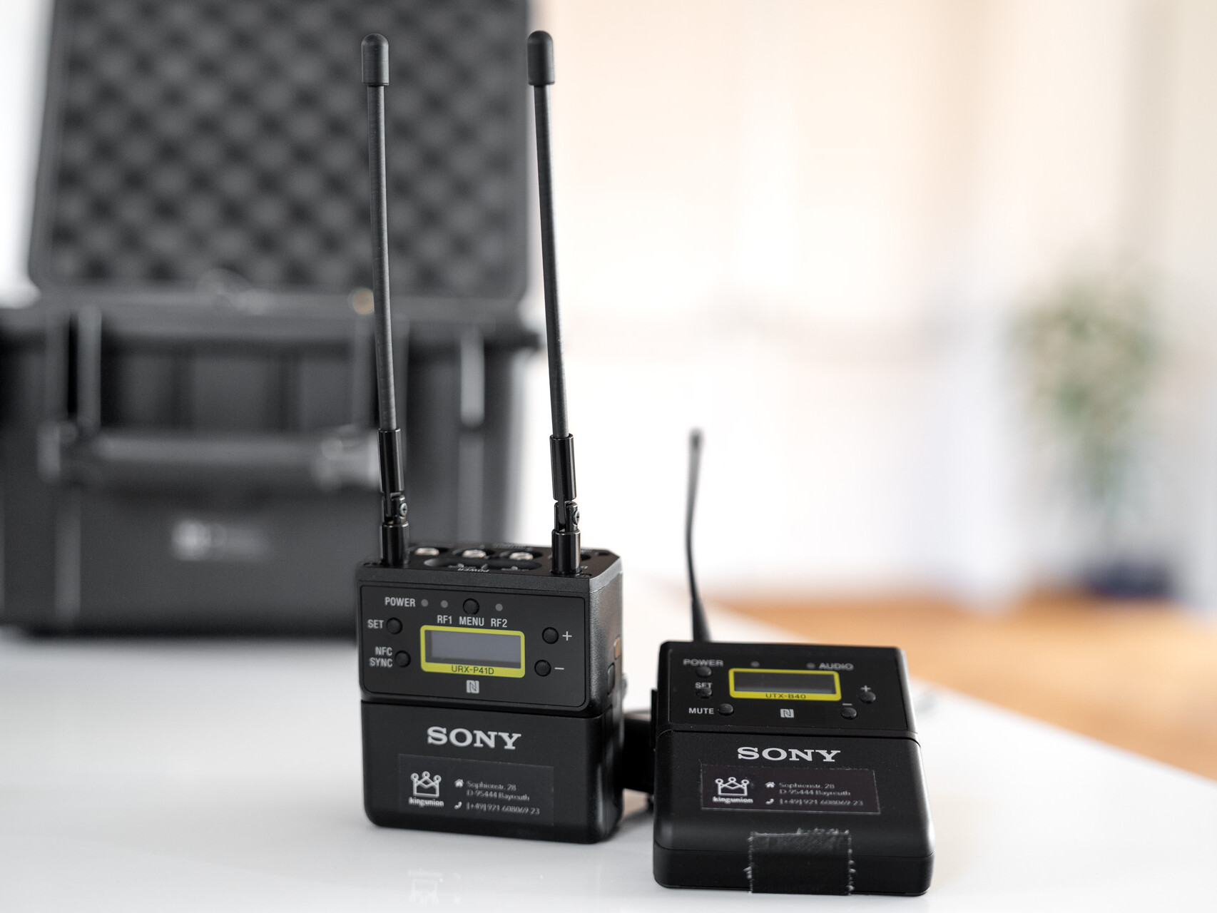 zwei Sony Lavalier-Mikrofon Sender vor einem offenen Koffer